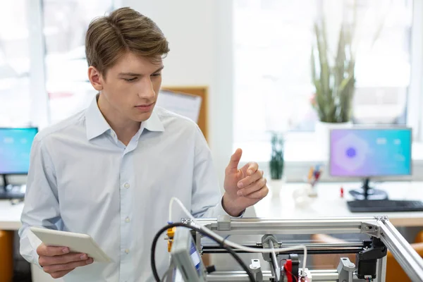 Bello giovane uomo che studia il meccanismo della stampante 3D — Foto Stock