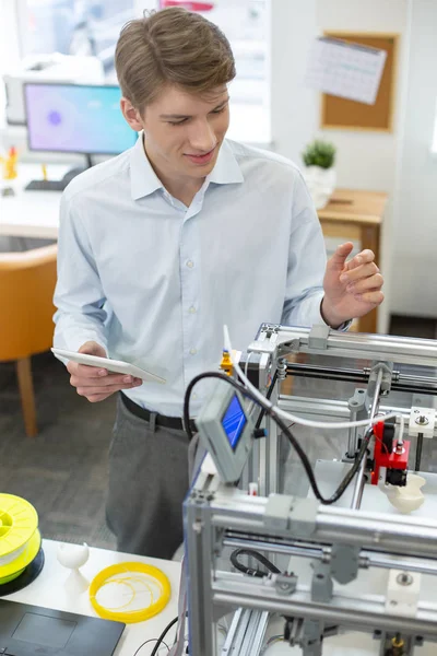 Веселый молодой человек, практикующийся в использовании 3D принтера — стоковое фото