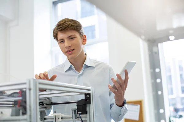 Handsome young man figuring out 3D printer configurations