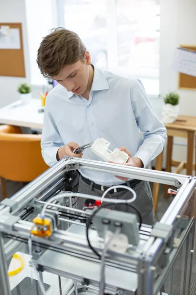 Pleasant young man figuring out height of printed model