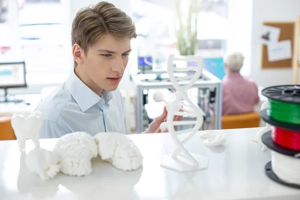 Веселий молодий чоловік вивчає 3D модель атома — стокове фото
