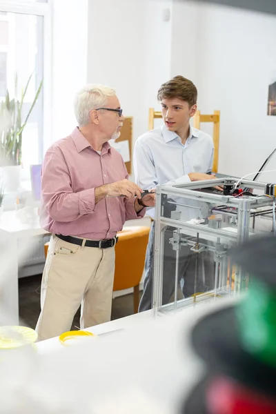 Hombre joven haciendo preguntas de supervisor sobre la impresión 3D —  Fotos de Stock