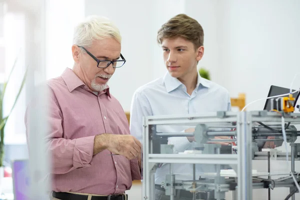 Engenheiro sênior mostrando estagiário como examinar impressora 3D — Fotografia de Stock