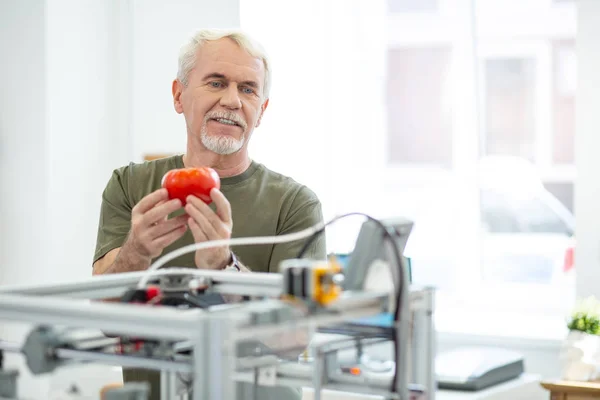 Gioioso uomo anziano ammirando il pomodoro rosso stampato con stampante 3D — Foto Stock