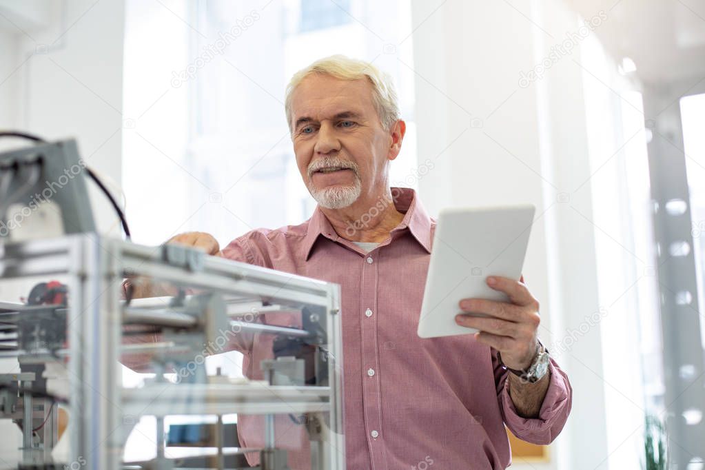 Senior office worker changing settings of 3D printer