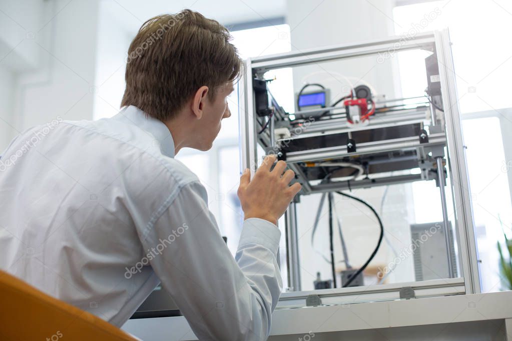 Pleasant young intern learning 3D printers work algorithm