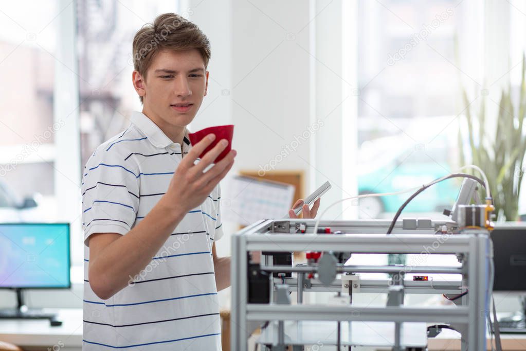 Cheerful young engineer looking for flaws in bell pepper