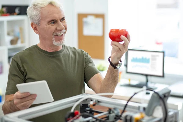 Alegre hombre mayor mirando modelo de tomate con sonrisa — Foto de Stock