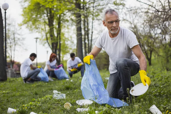 Voluntario senior enfocado recogiendo basura — Foto de Stock