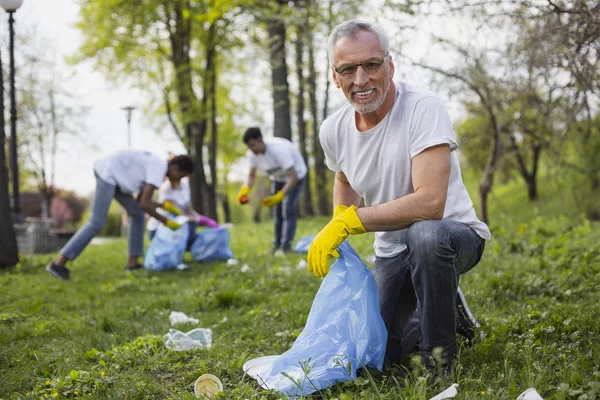 Feliz voluntario senior recogiendo basura — Foto de Stock