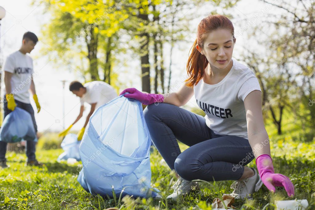 Focused female volunteer collecting litter