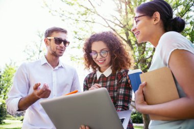 Güvenilir arkadaş. Onu laptop ve arkadaşları yanında ayakta tutan neşeli kıvırcık saçlı kadın