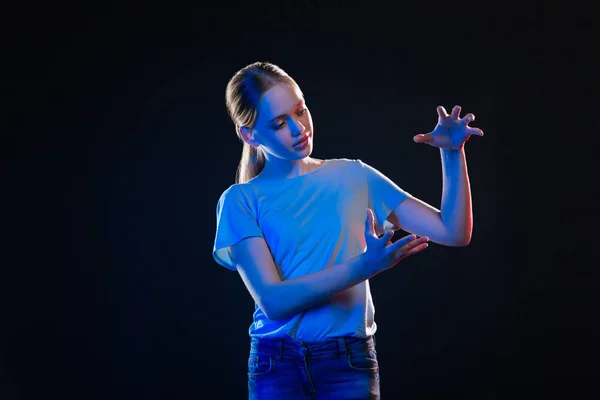 Serious young woman standing against black background — Stock Photo, Image