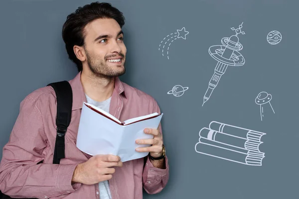 Optimistic student reading a book and thinking about other planets — Stock Photo, Image