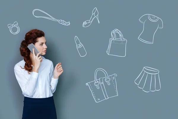 Спокойная деловая женщина разговаривает по телефону и покупает одежду — стоковое фото