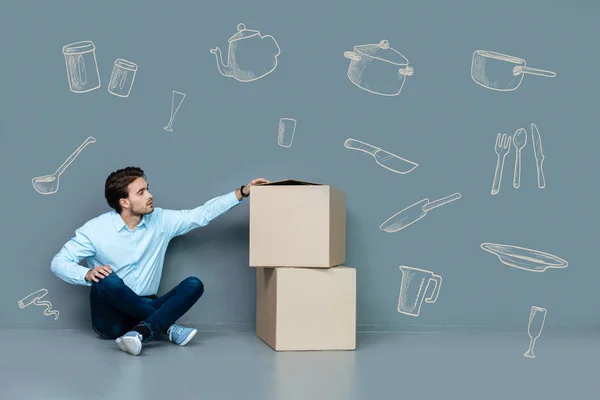 Joven mirando las cajas después de mudarse a un nuevo piso — Foto de Stock