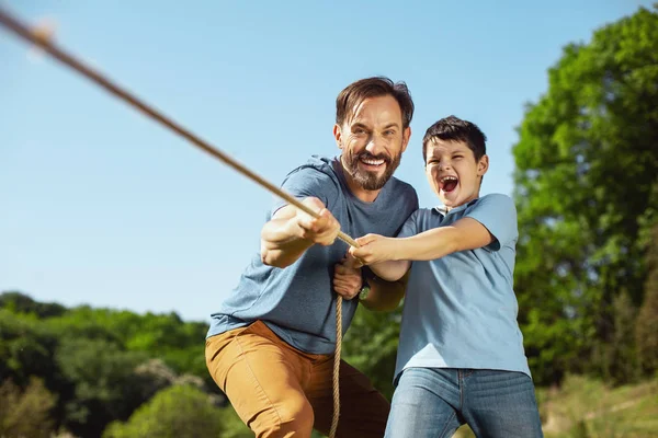 Família feliz puxando uma corda no parque — Fotografia de Stock