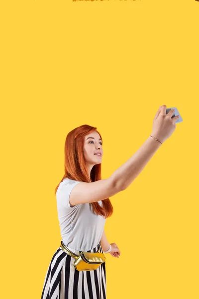 Позитивная рыжая женщина смотрит в камеру смартфона — стоковое фото
