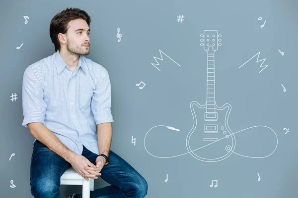 Nachdenklicher Musiker, der allein sitzt und von einer neuen Gitarre träumt — Stockfoto