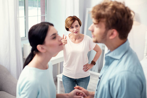 Старая несчастная женщина смотрит на супружескую пару
