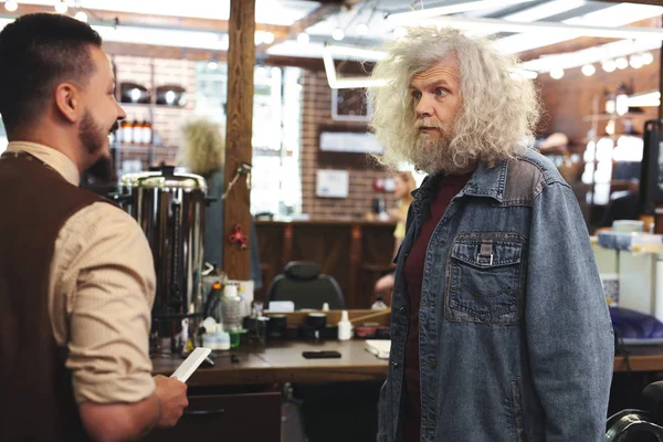 Surprised mature man talking with barber — Stock Photo, Image