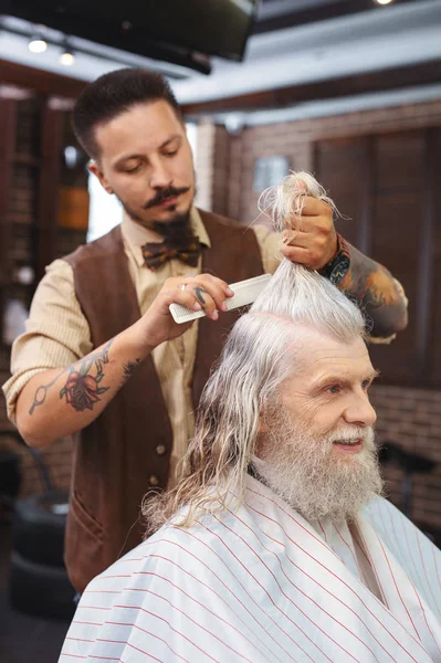 Serious bearded hairdresser serving client — Stock Photo, Image