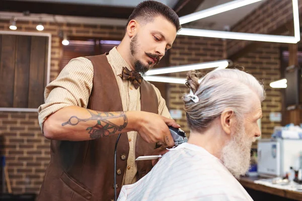 Концентрированный брюнетка мужчина, работающий в парикмахерской — стоковое фото
