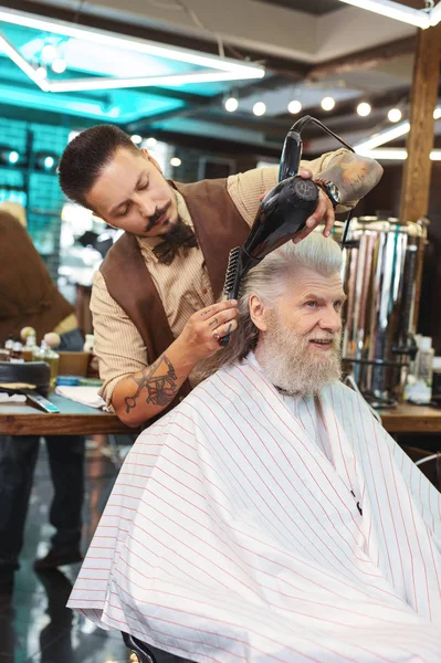 Serious barber drying hair of his client — Stock Photo, Image