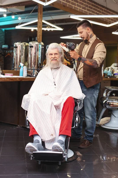 Attentive hairdresser drying long male hair