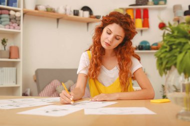 Genç sanatçı oturma yeşil bitki yakınındaki çizim