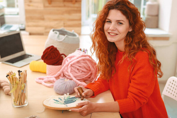 Happy freelancer embroidering picture during break