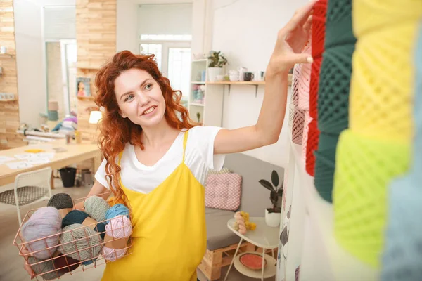 Rothaarige Kunsthandwerkerin hebt die Hand, um einen Faden zu nehmen — Stockfoto