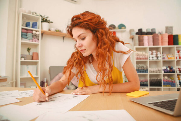 Молодой художник с рыжими волосами рисует эскизы
