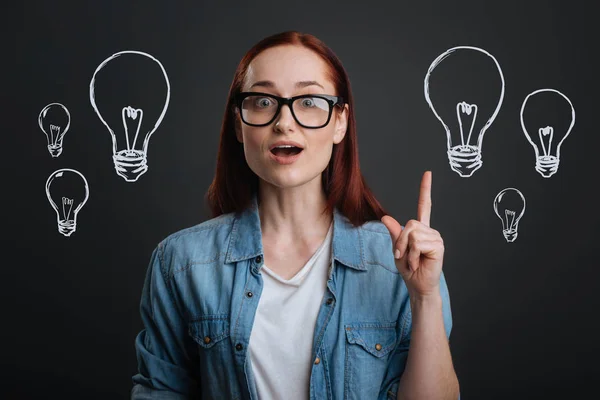 Diseñadora inteligente apuntando con el dedo hacia arriba mientras se le ocurre una idea brillante —  Fotos de Stock