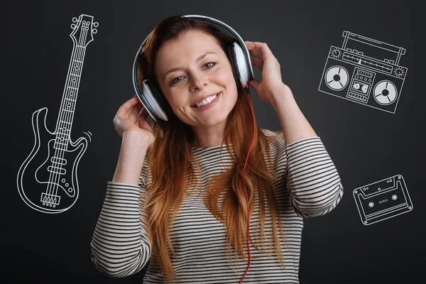 Wesoły kobieta uśmiechając się i słuchanie muzyki w jej słuchawki — Zdjęcie stockowe