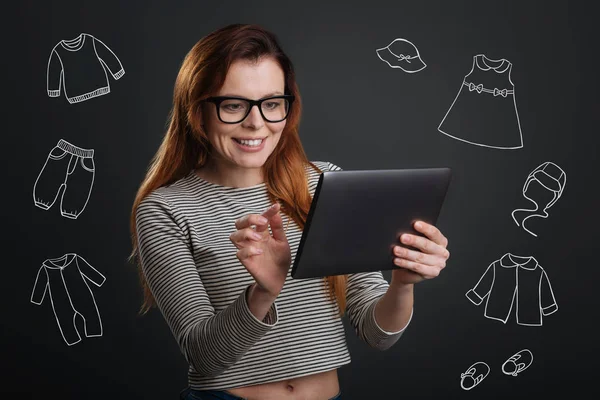 Mujer alegre sosteniendo una tableta y haciendo compras en línea — Foto de Stock
