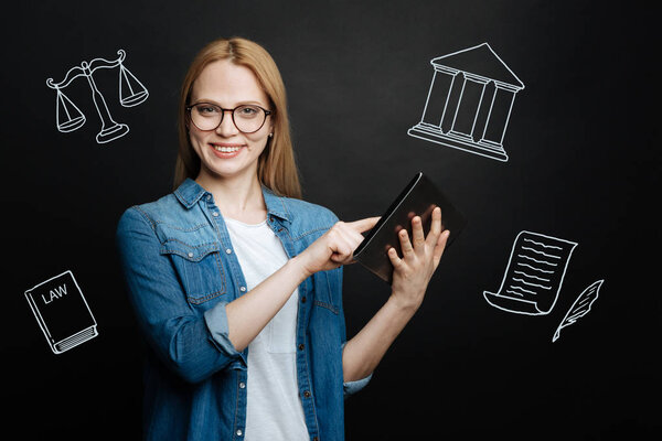 Cheerful lawyer standing with a tablet and looking confident