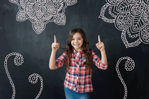 Positive child smiling and pointing to the pictures on the wall — Stock Photo, Image