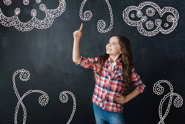 Cheerful girl pointing her finger up while talking about her holidays — Stock Image Cheerful girl pointing her finger up while talking about her holidays Stock Photo