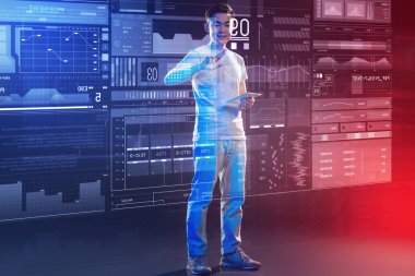 İyi bir duygu. Gülümseyen ve süre onun elinde modern bir tablet ile ayakta ve kutsal kişilerin resmi üstünde belgili tanımlık perde dokunmadan iyimserim olumlu hevesli genç web geliştirici