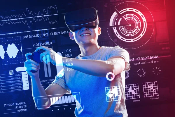 Homem animado segurando um console de jogo enquanto usava óculos de realidade virtual — Fotografia de Stock