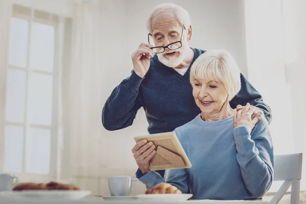 Encantado anciano sosteniendo sus gafas — Foto de Stock