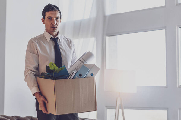 Depressed cheerless man holding a box