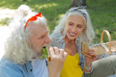 Bir sandviç tutan memnun güzel kadın