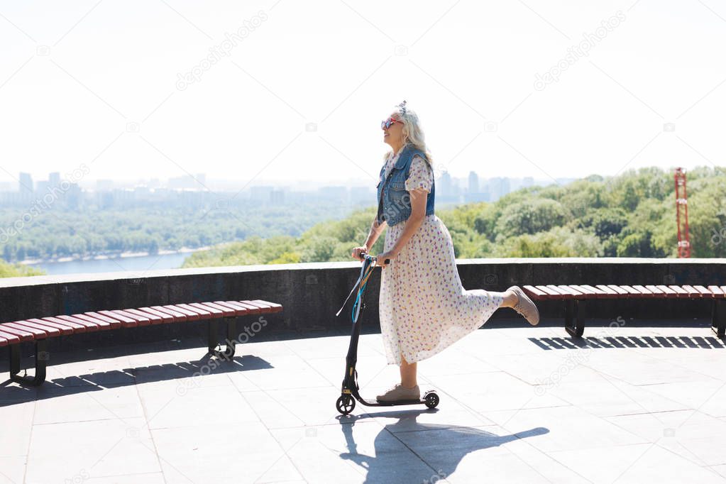 Happy elderly woman riding a scooter