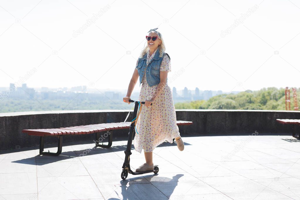 Joyful positive woman using a scooter