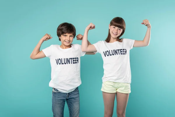 Voluntarios alegres mostrando sus músculos — Foto de Stock