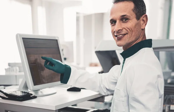 Portrait of pleased laboratory assistant pointing at computer screen — Stock Photo, Image