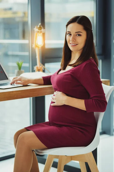 Beautiful pregnant secretary touching her belly and smiling — Stock Photo, Image