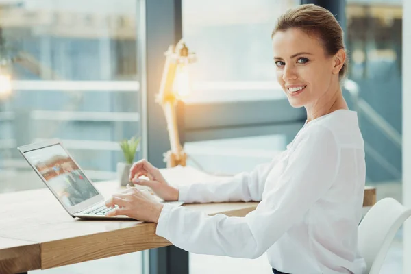 Glada boss leende medan du arbetar på den bärbara datorn — Stockfoto